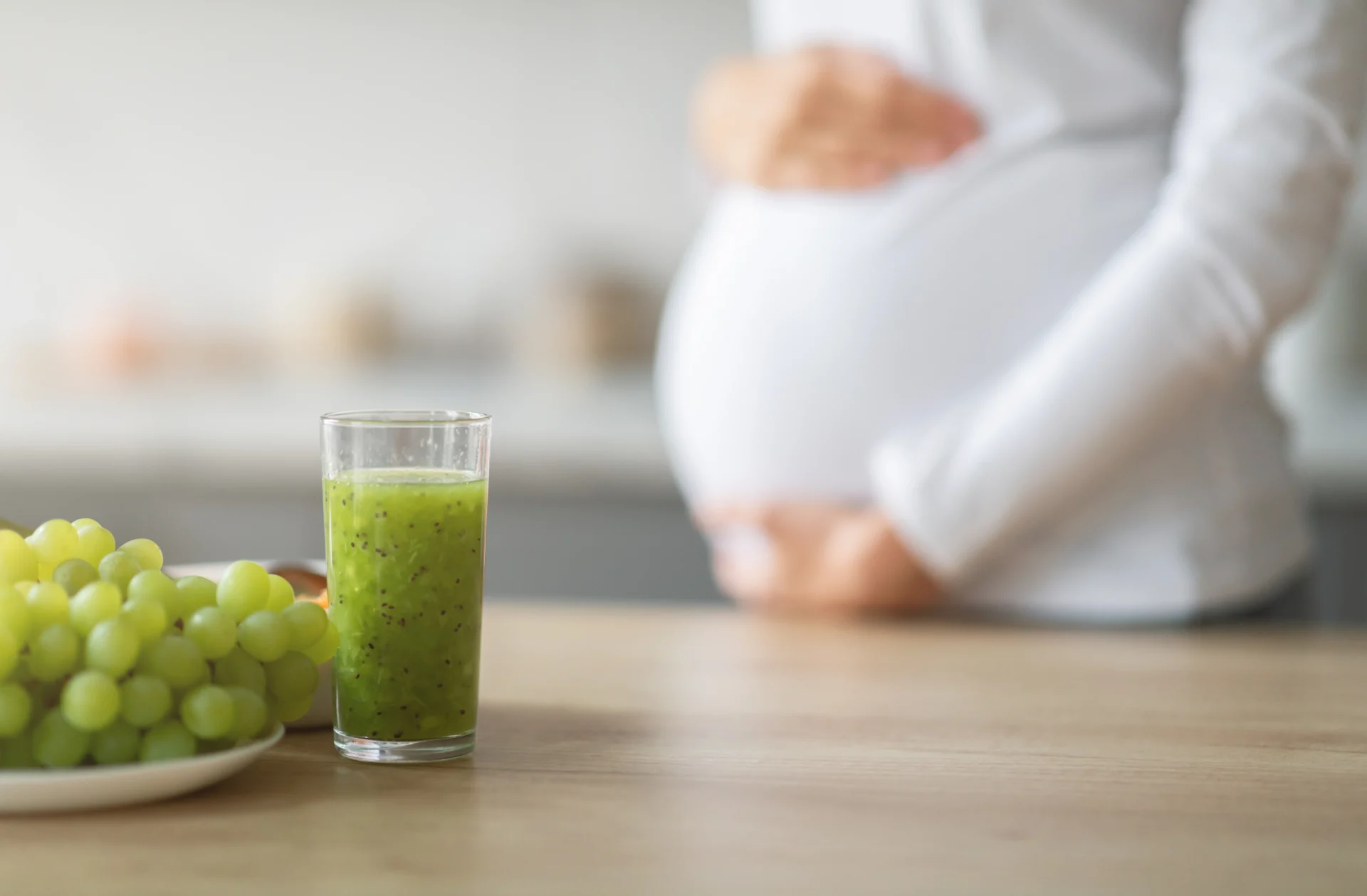 Mujer embarazada junto a jugo verde